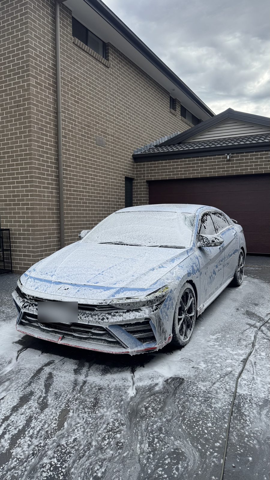 Hyundai i30 Sedan N covered in thick snow foam during the pre-wash