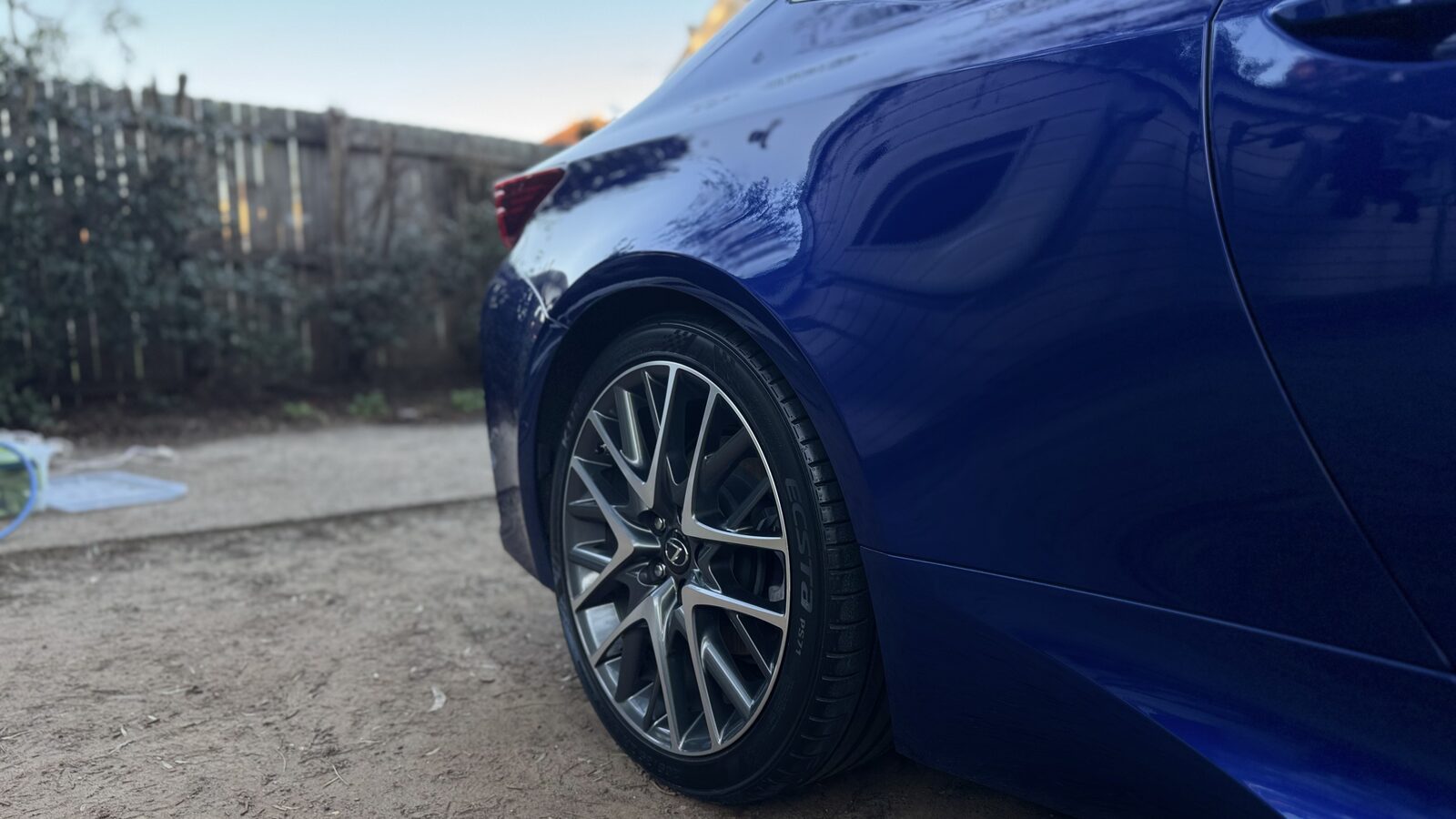 Low angle of the glossy blue front guard and alloy wheel of a Lexus RC350