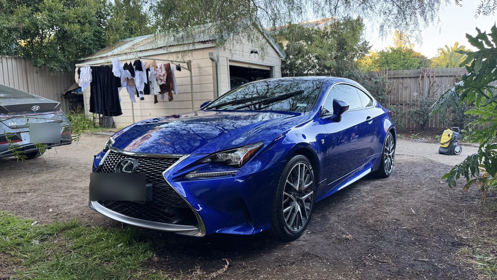 Blue Lexus RC350 F Sport coupe after paint correction and ceramic sealant, parked in a backyard