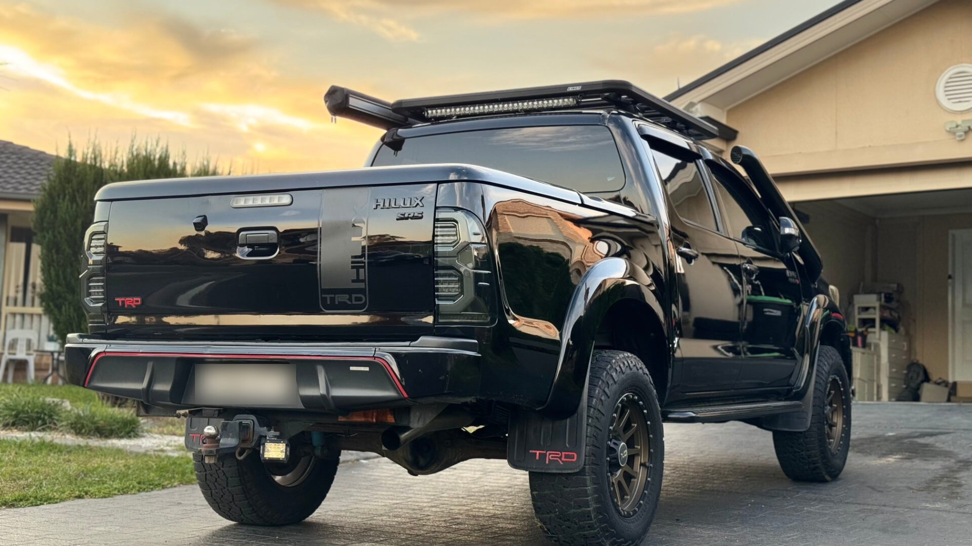 Rear of a black Toyota Hilux SR5 with a deep gloss finish at sunset